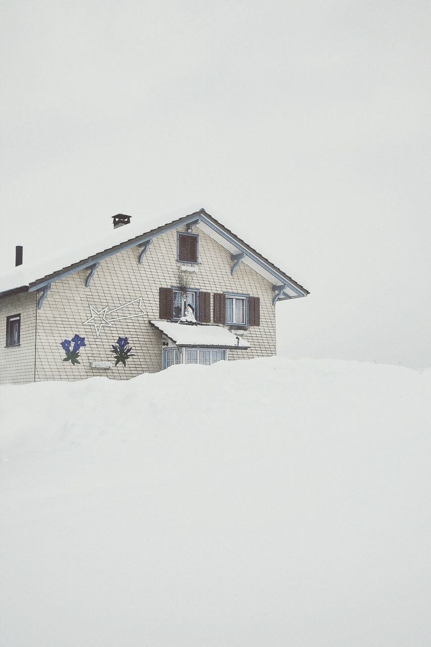 Low angle view of house in snow against clear sky