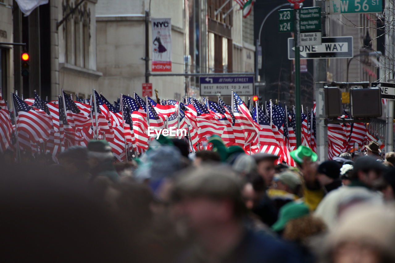 Crowd with american flags by buildings in city