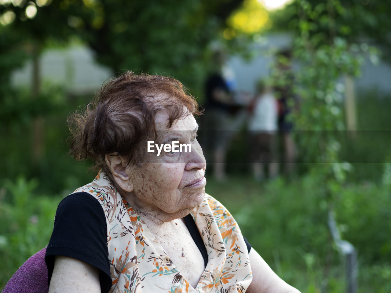 Thoughtful senior woman looking away while sitting in back yard
