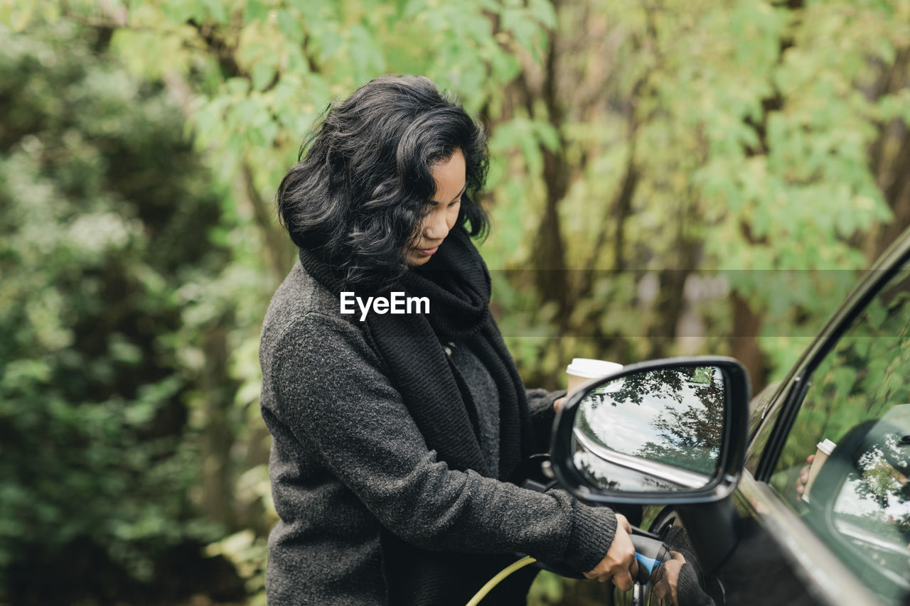 Mid adult woman charging electric car