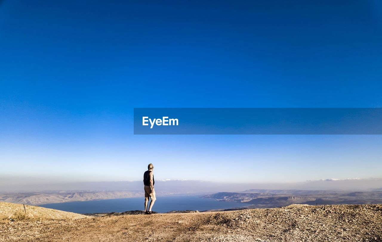 Man standing on mountain against blue sky