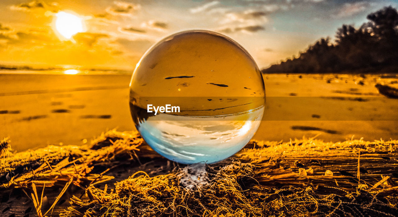 CLOSE-UP OF CRYSTAL BALL ON GLASS AGAINST SKY