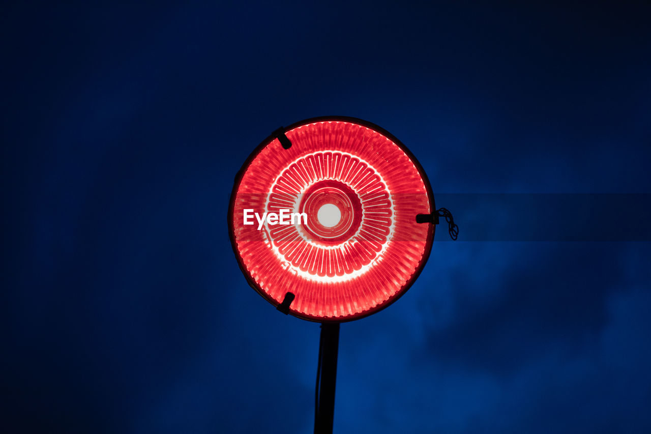 Low angle view of illuminated street light against cloudy sky at night