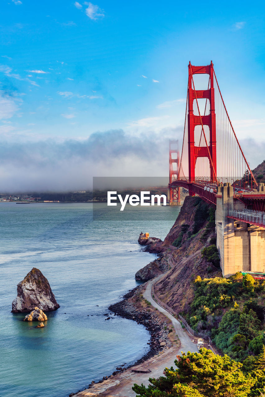 water, architecture, sky, built structure, travel destinations, sea, nature, coast, transportation, travel, bridge, cloud, tourism, ocean, tower, shore, land, suspension bridge, bay, scenics - nature, bay of water, city, blue, beauty in nature, red, no people, landmark, landscape, beach, outdoors, building exterior, horizon, environment, vacation, building, tranquility, reflection, coastline, history, holiday, the past, day