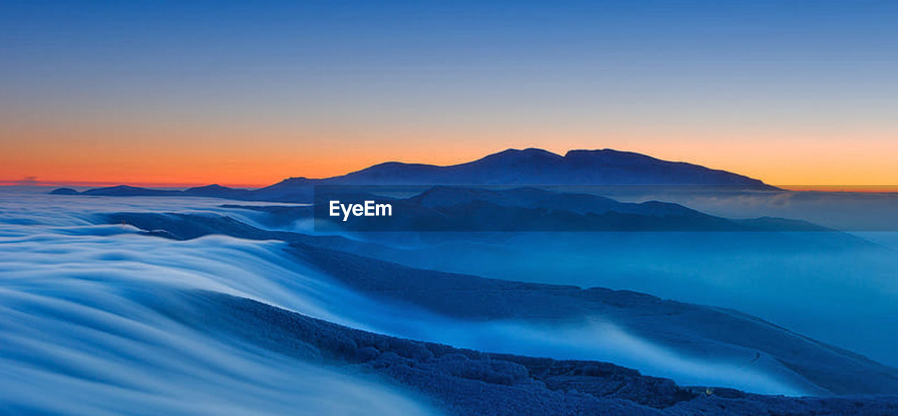 SCENIC VIEW OF MOUNTAINS AGAINST BLUE SKY AT SUNSET
