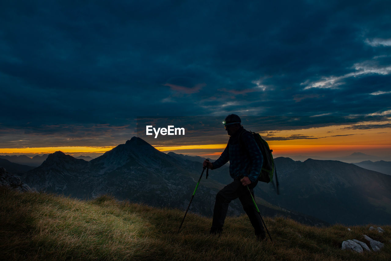 Woman on mountain against sky during sunset