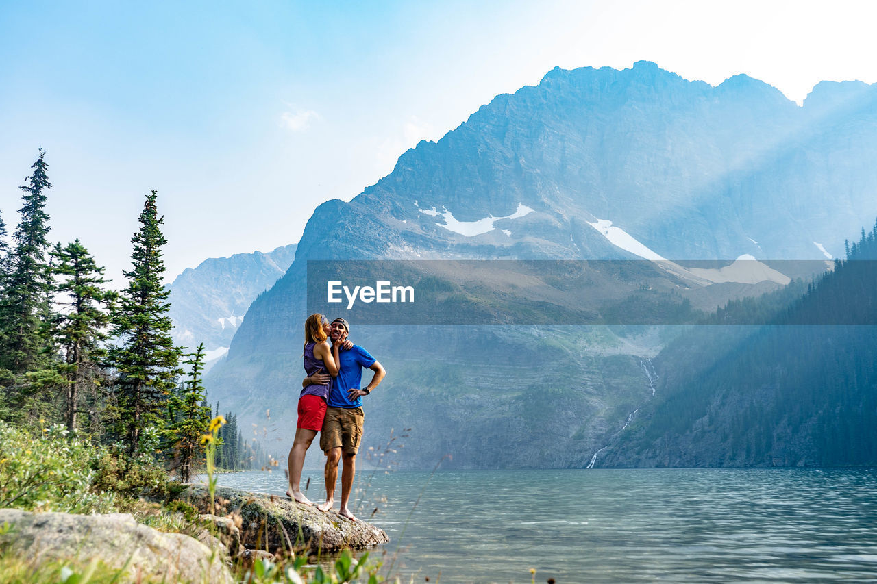 Couple standing by lake against mountain