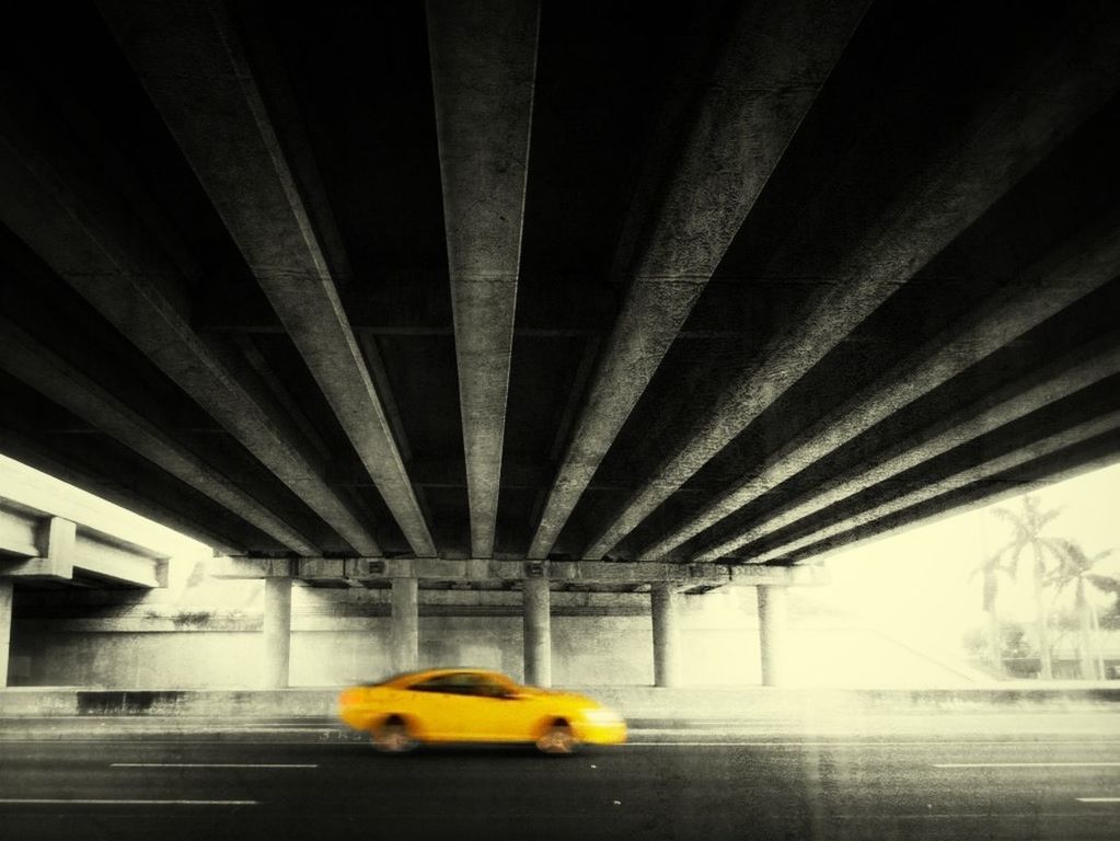 Blurred motion of yellow car on street below bridge