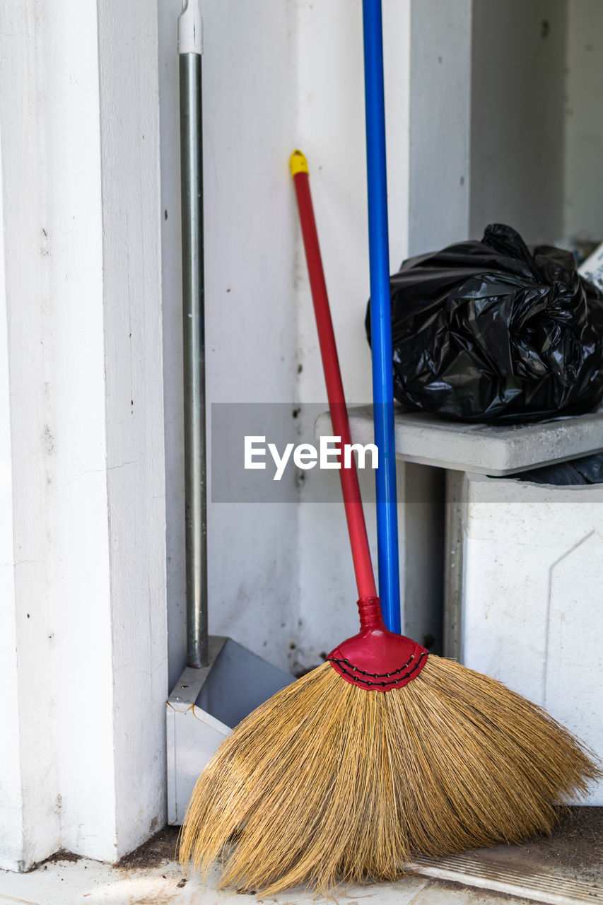 Close-up of broom and cleaning equipment against wall