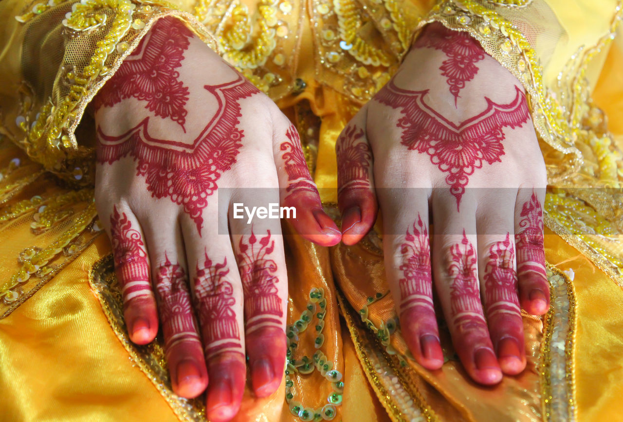 Midsection of bride showing henna tattoo during wedding ceremony