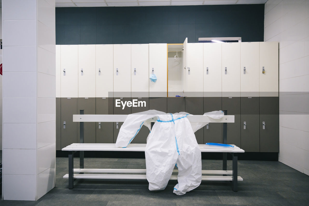 Protective wear and face shield kept on bench in locker room at hospital