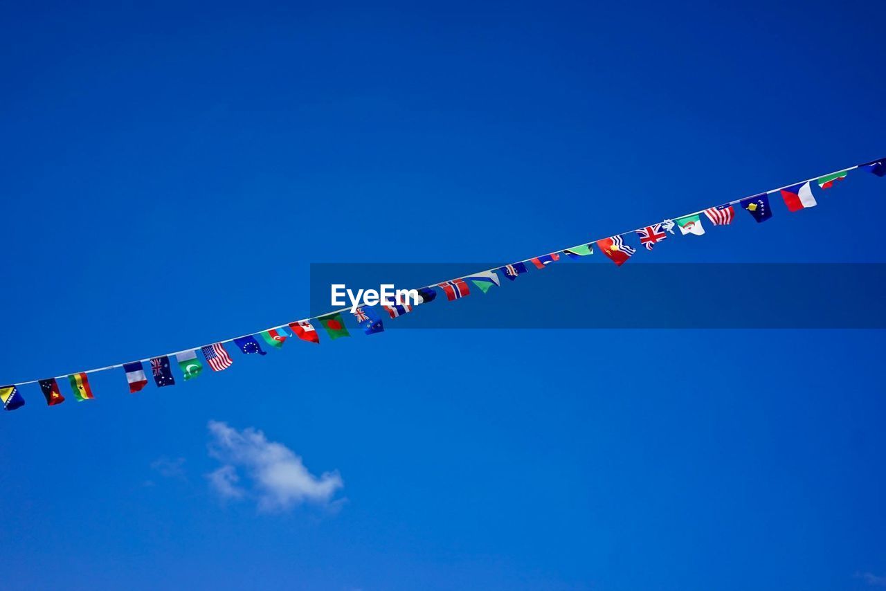 Low angle view of bunting flags against blue sky