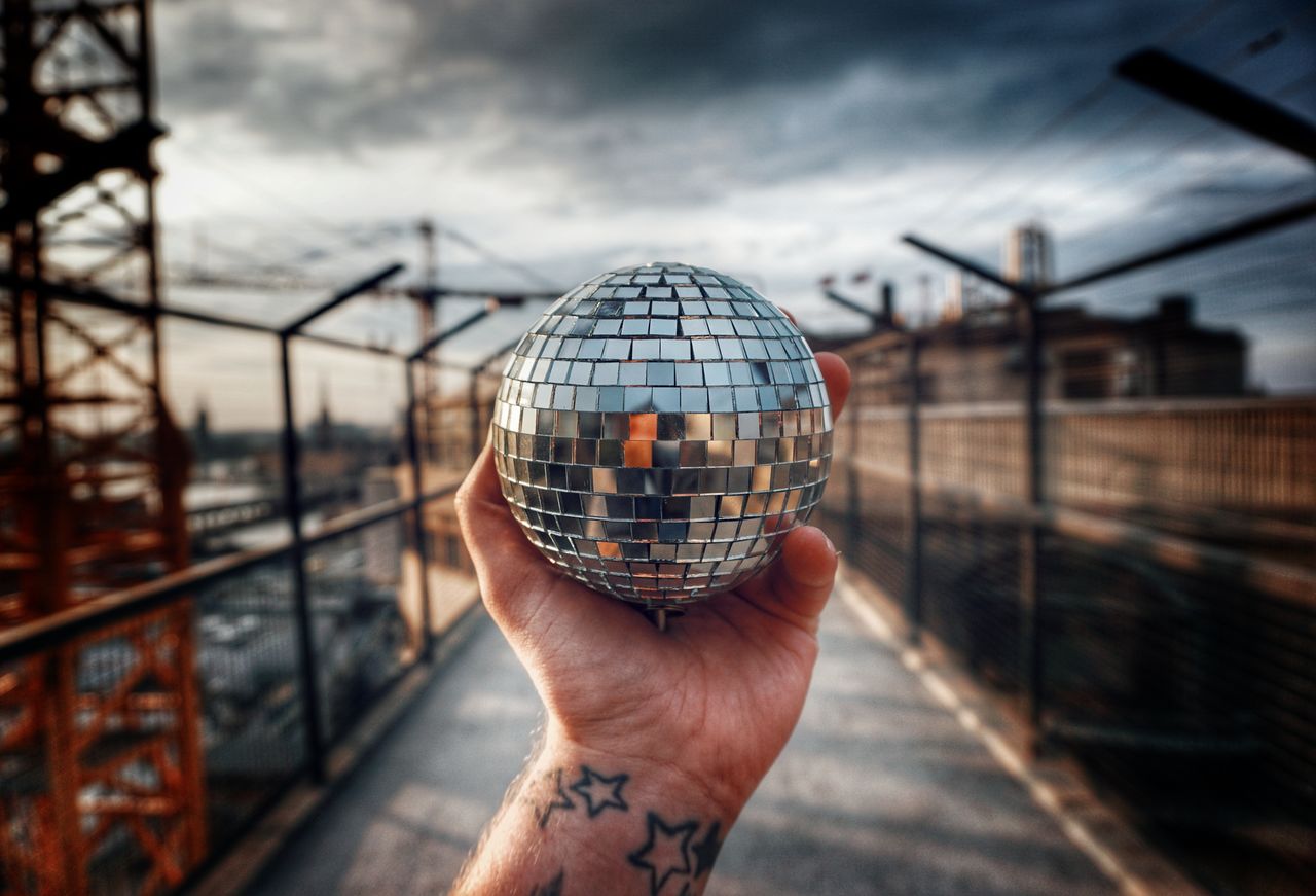 Cropped hand holding disco ball outdoors