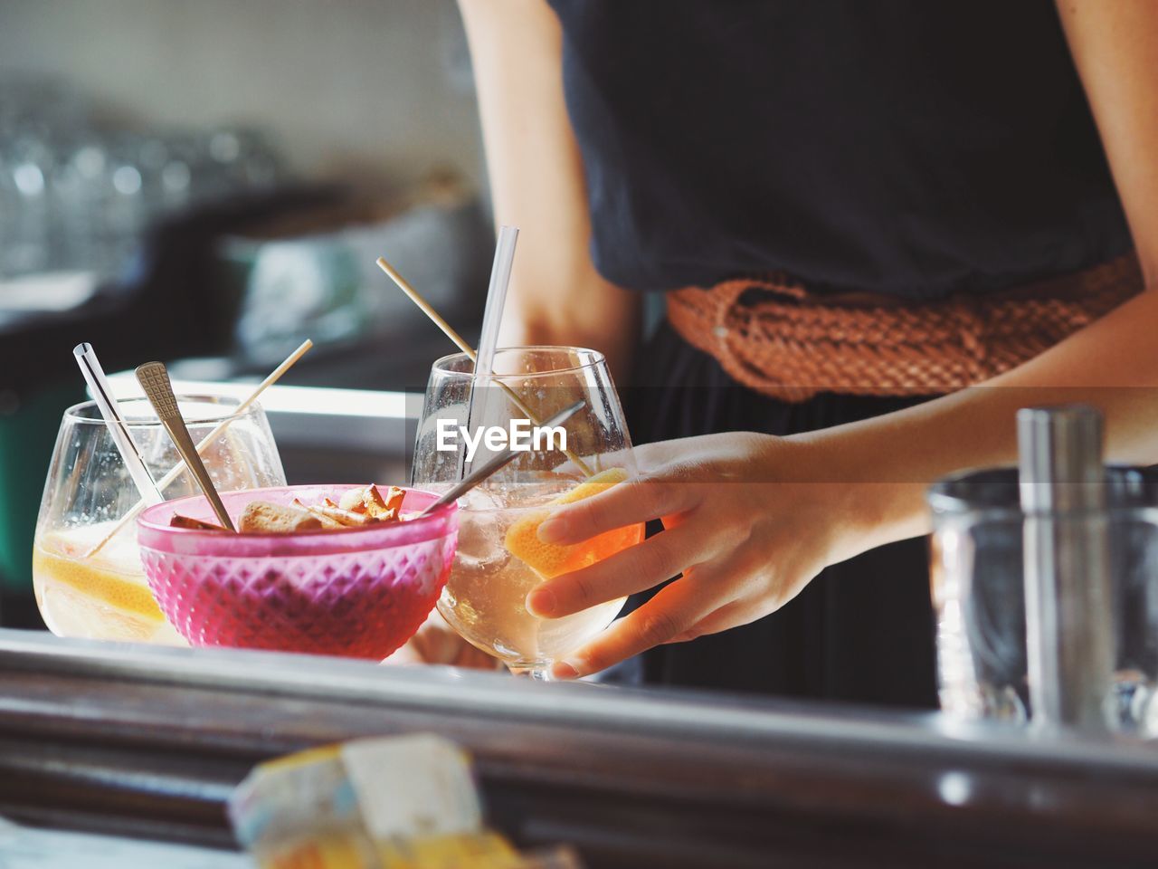 Midsection of waitress serving food and drinks on restaurant table