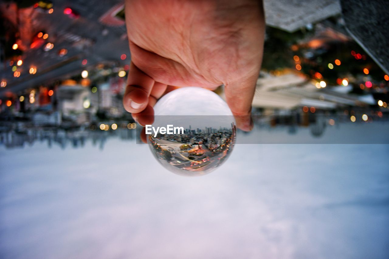 DIGITAL COMPOSITE IMAGE OF HAND HOLDING CRYSTAL BALL WITH REFLECTION