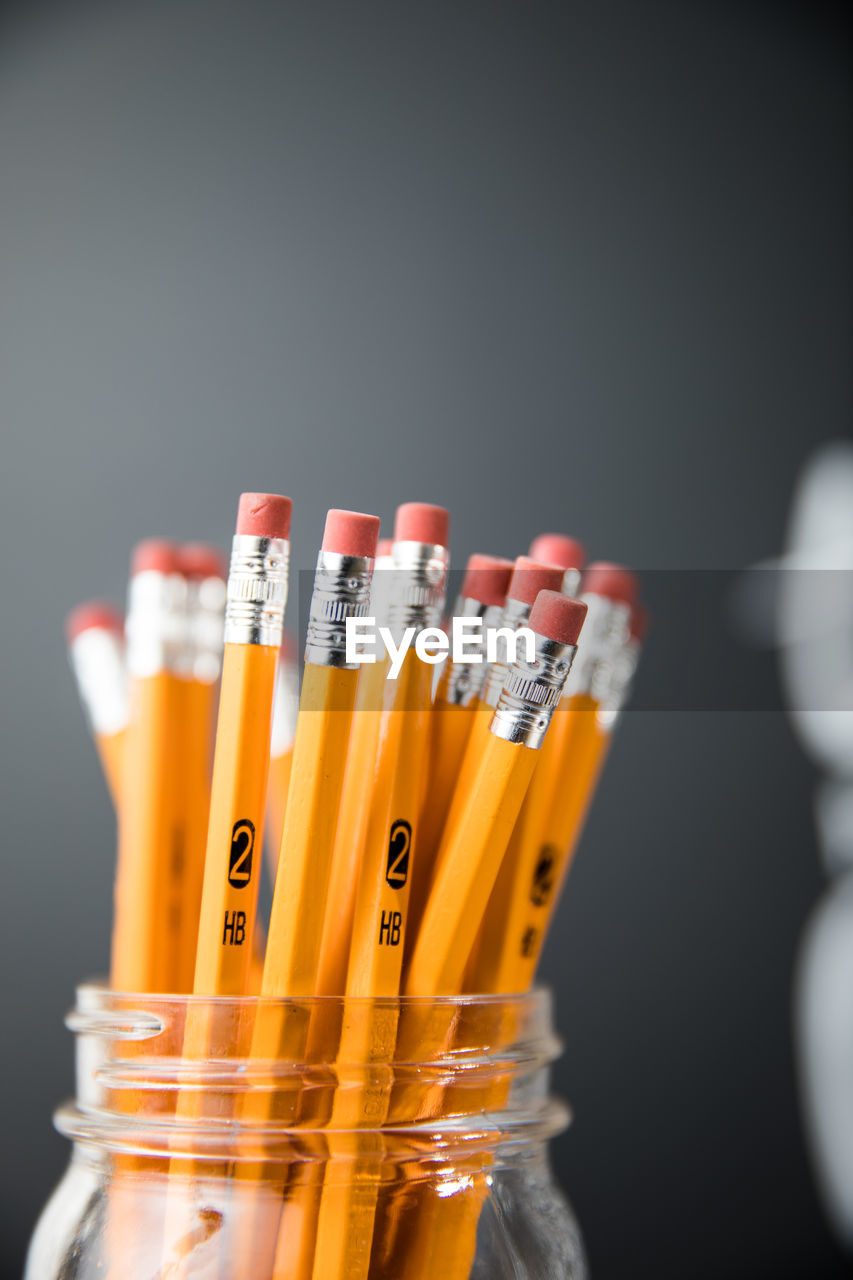 Close-up of pencils in jar against blackboard