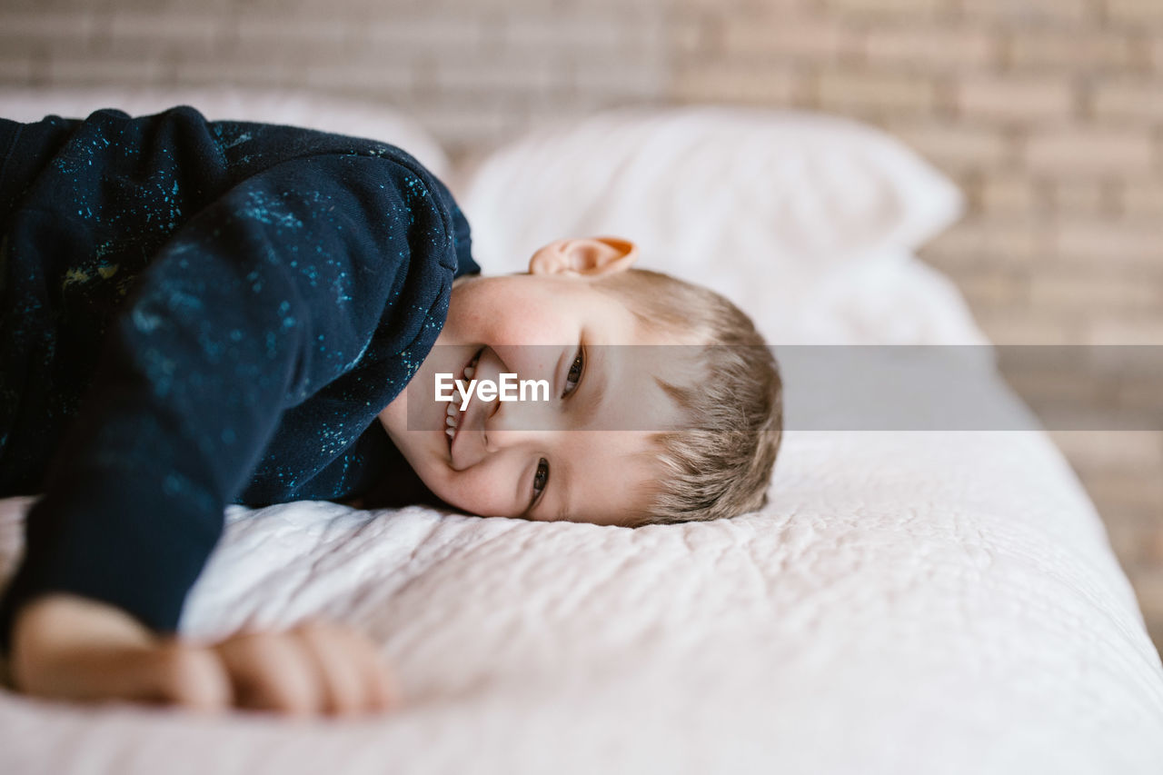Portrait of smiling boy on bed at home