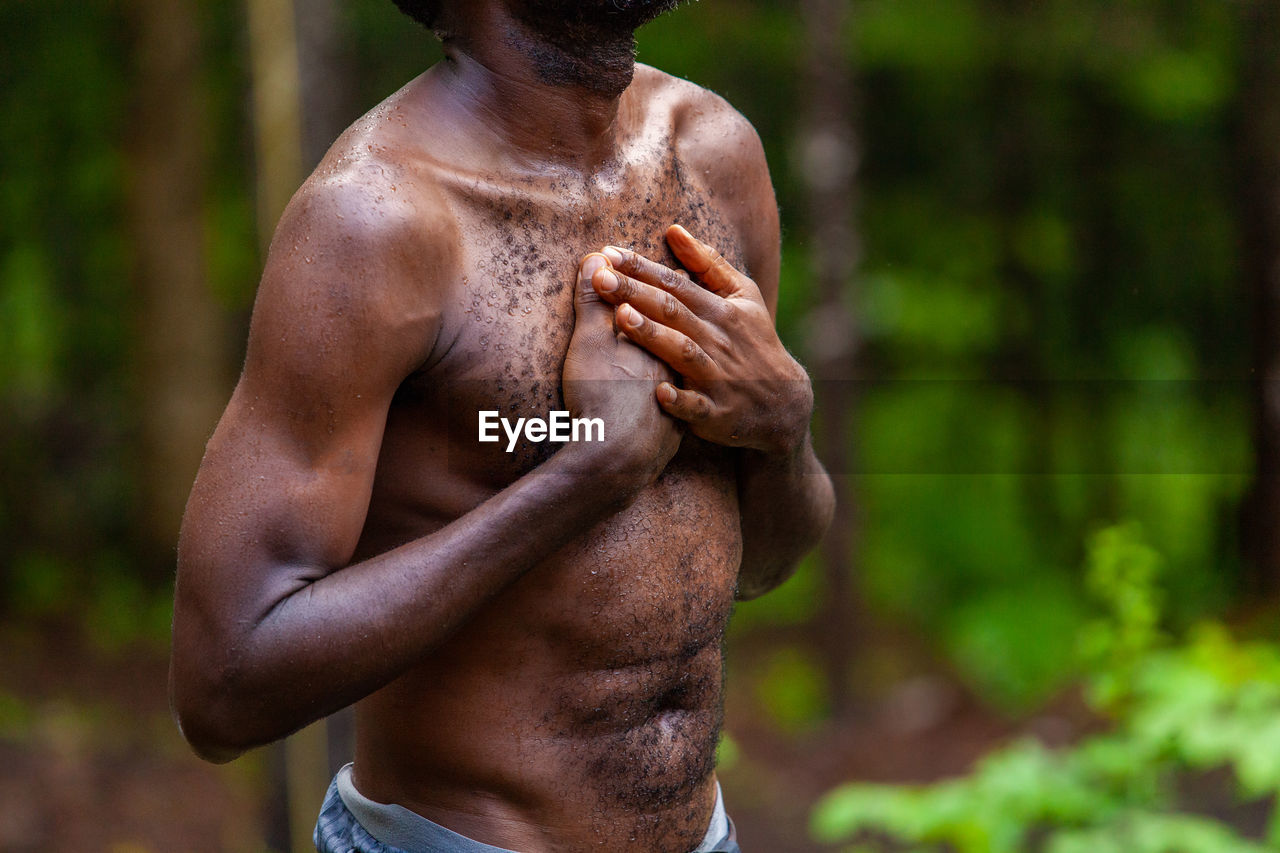 Midsection of shirtless man standing against blurred background