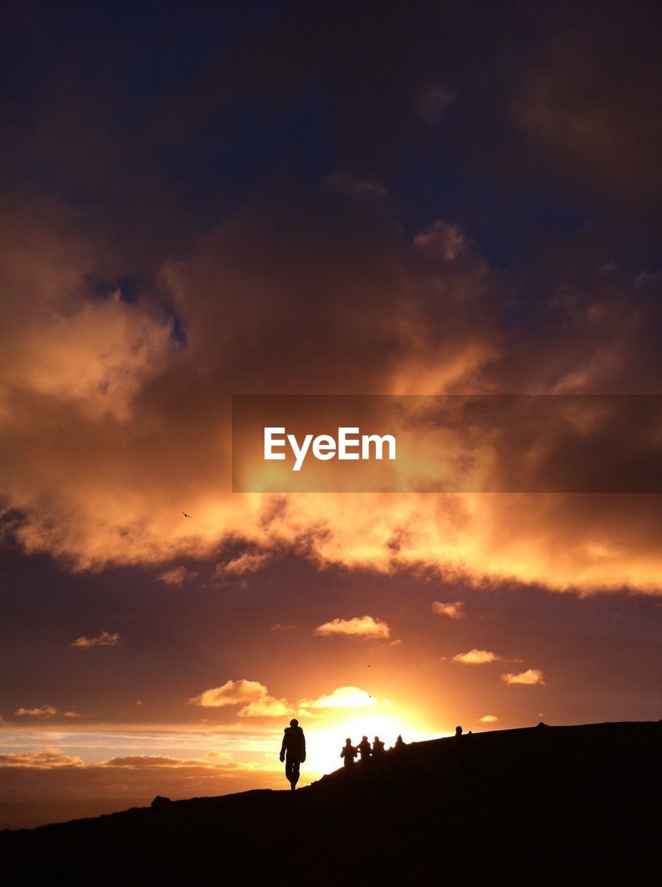 LOW ANGLE VIEW OF SILHOUETTE MEN AGAINST ORANGE SKY