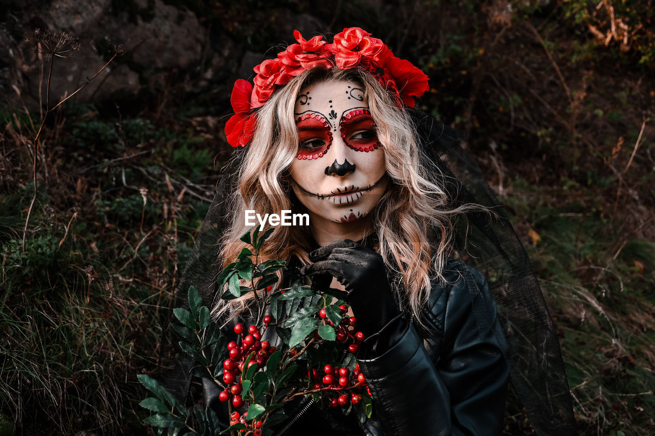 Closeup portrait of calavera catrina. young woman with sugar skull makeup and red flowers. dia 