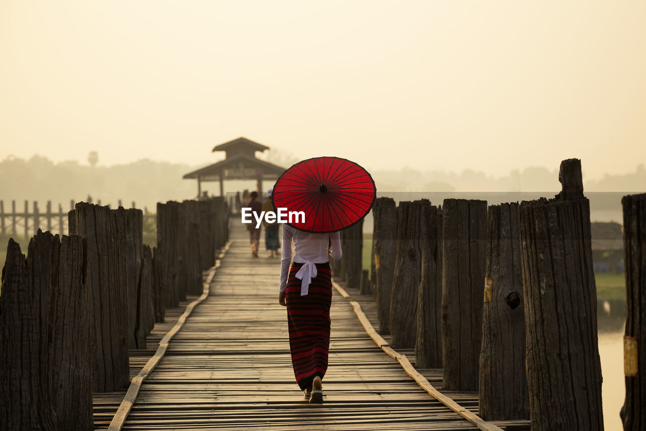 Rear view of woman with traditional umbrella on u bein bridge