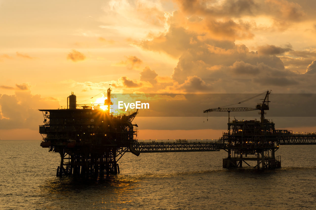 Seascape of golden hour offshore with silhouette of an oil production platform 