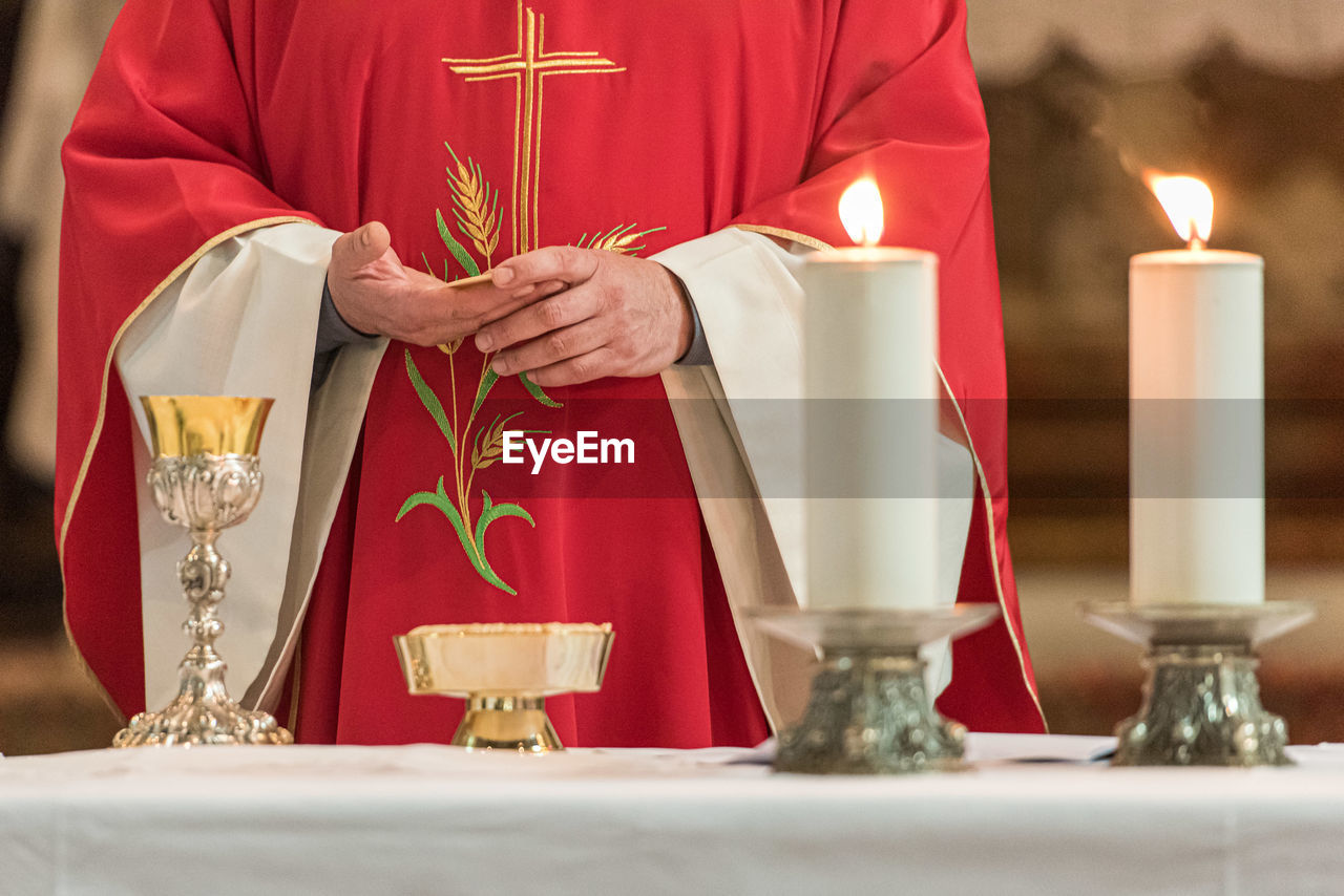 Midsection of priest praying at table in church