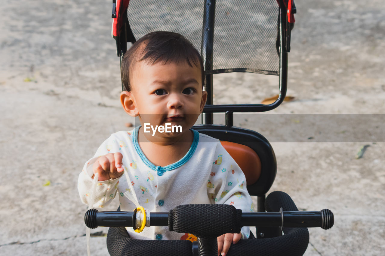 Portrait Of Cute Baby Boy Cycling On Land On Eyeem