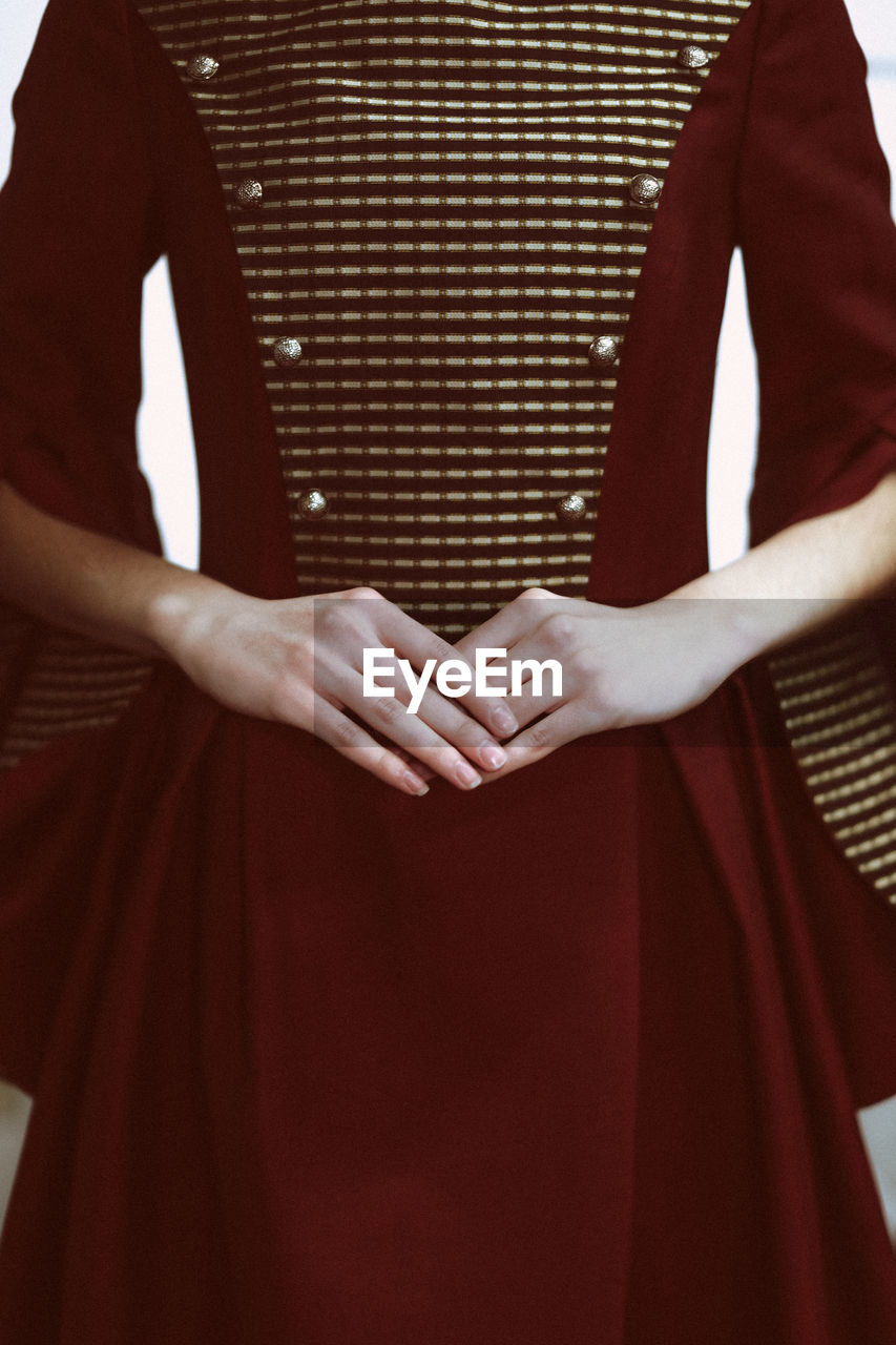 Female hands against the vintage dark red elegant dress