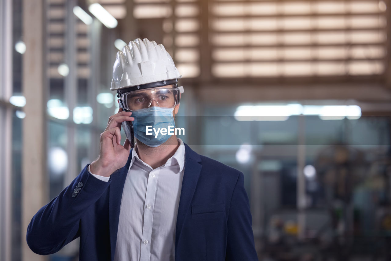 Mechanical worker with mask talking on the phone in a factory person