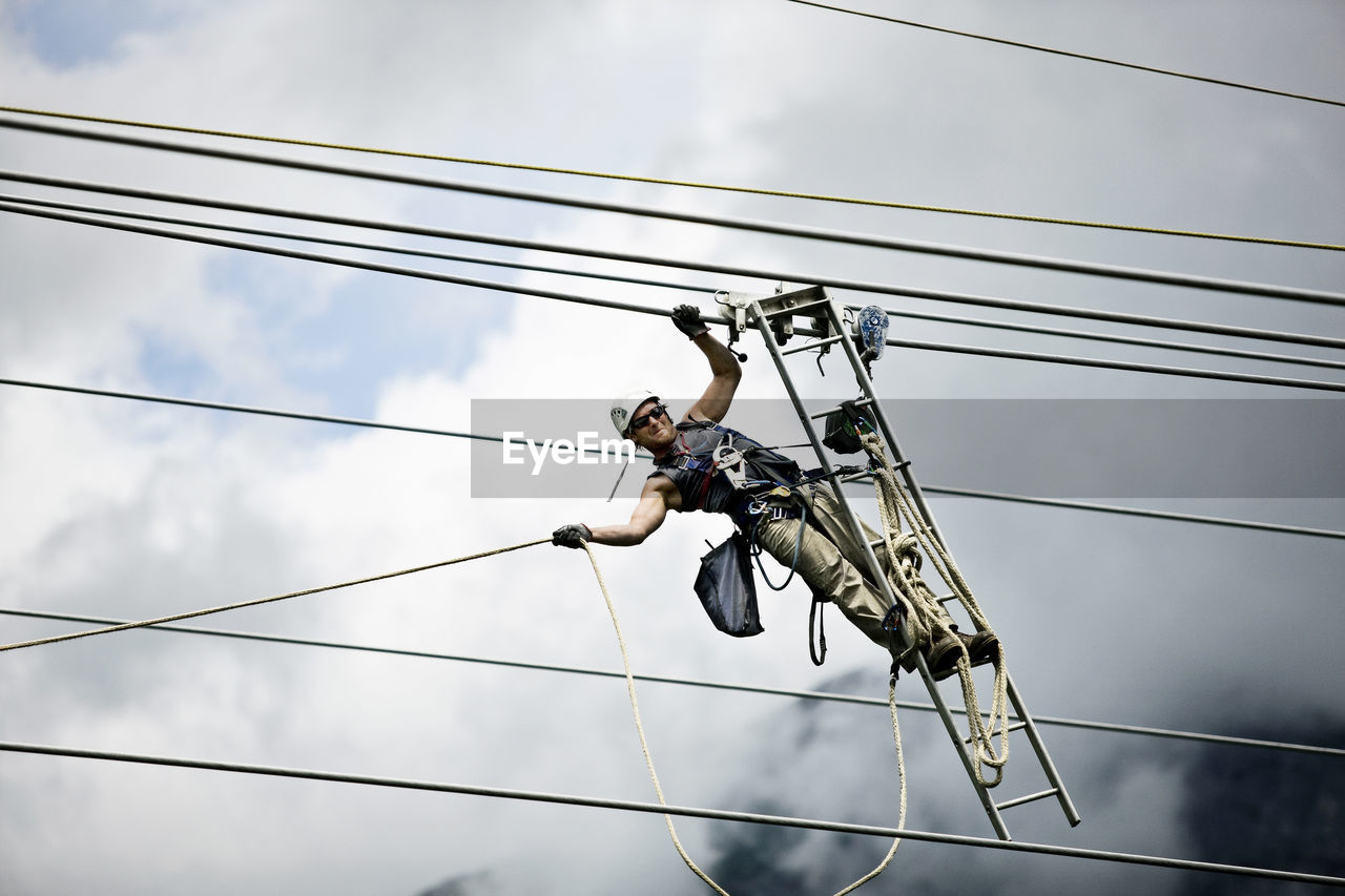 Fitter with ladder, pulling along high-voltage power line