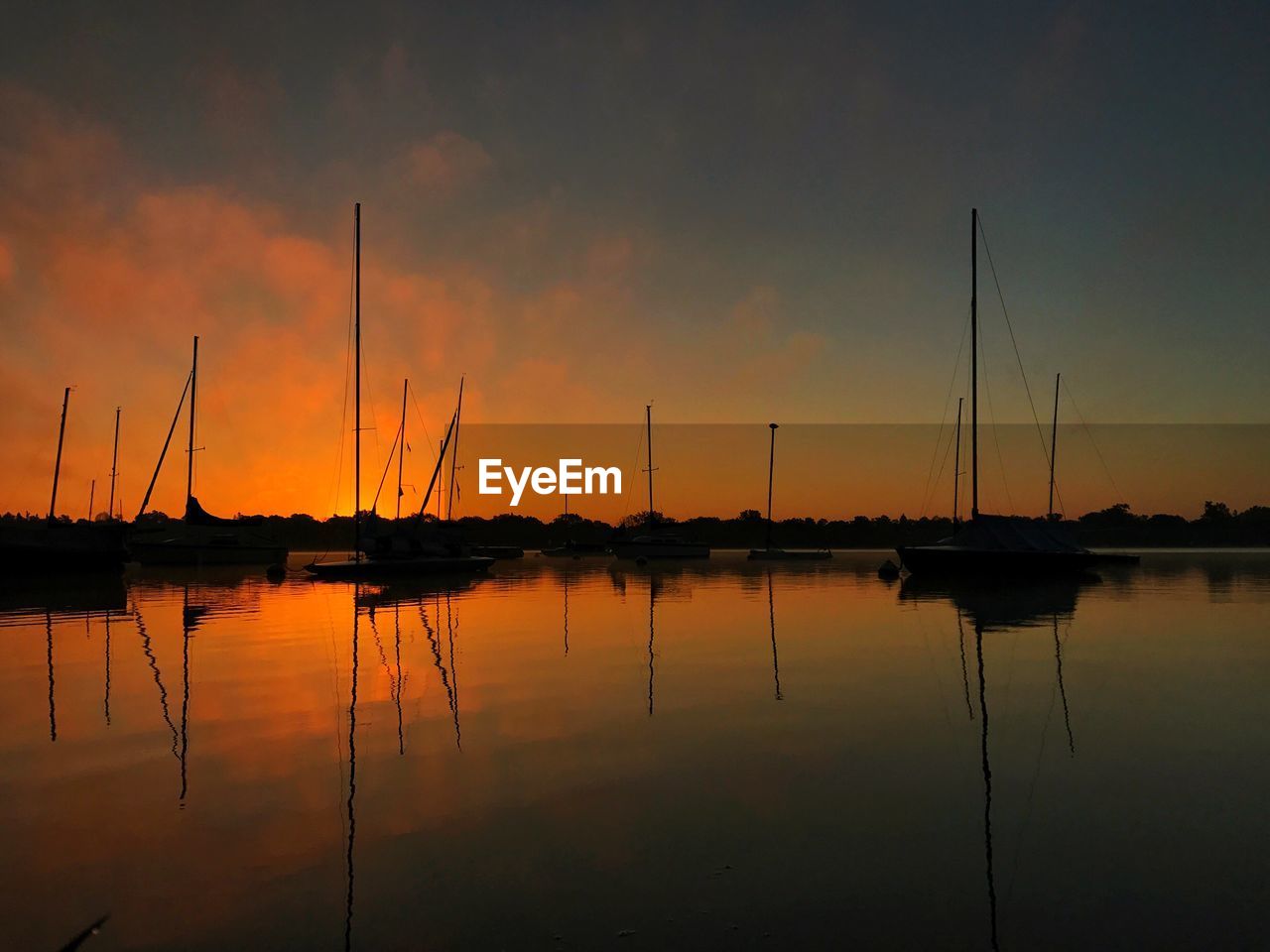 Sailboats in calm sea at sunset