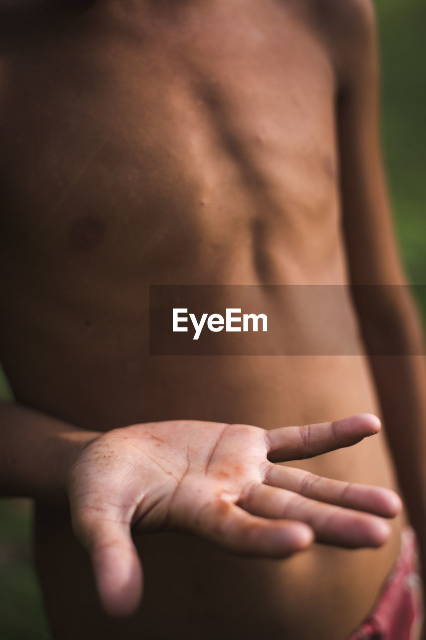 Midsection of shirtless man showing hands