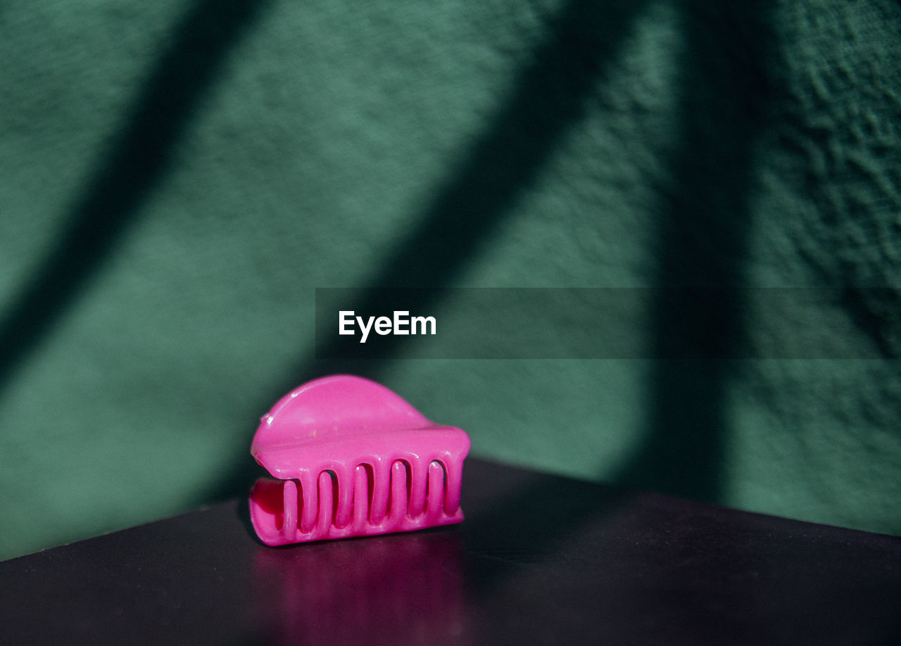 A pink object behind a green wall
