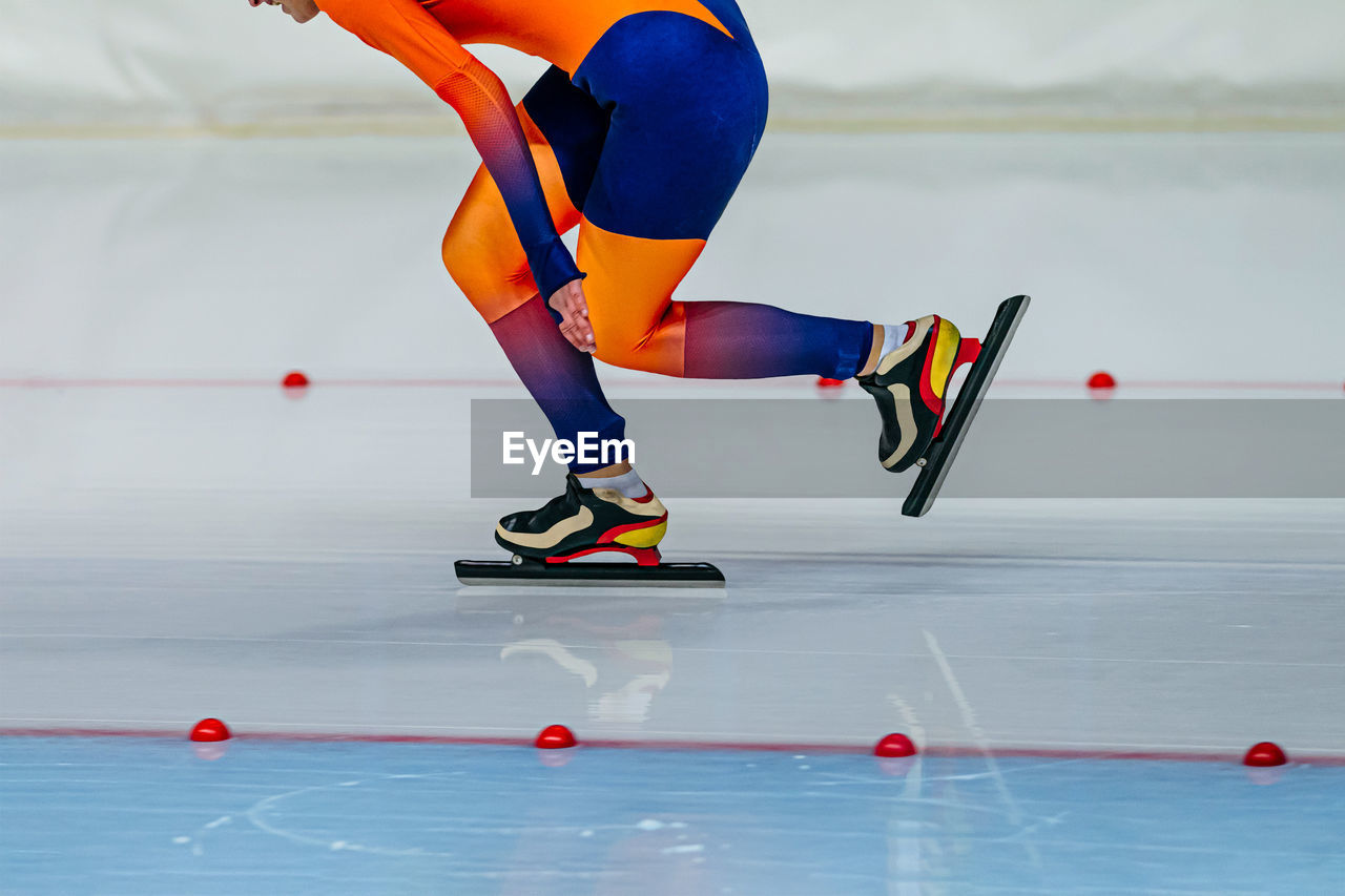 Speed skater athlete in bright orange skin suit