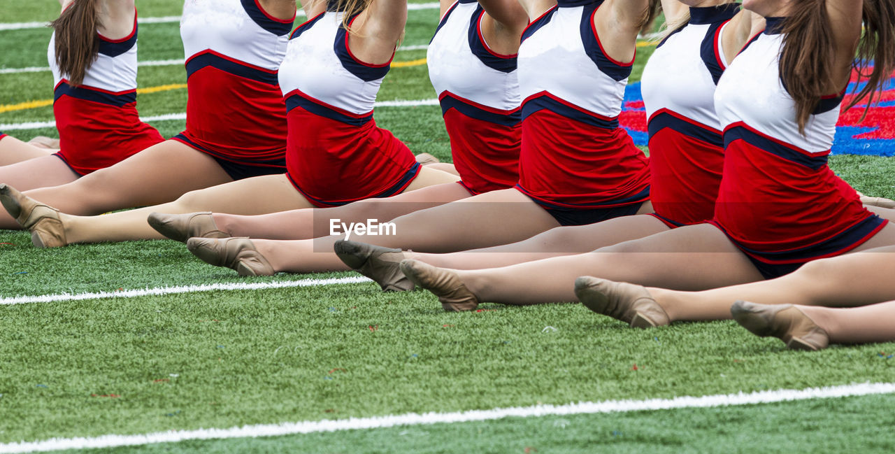 Low section of cheerleaders standing on grass