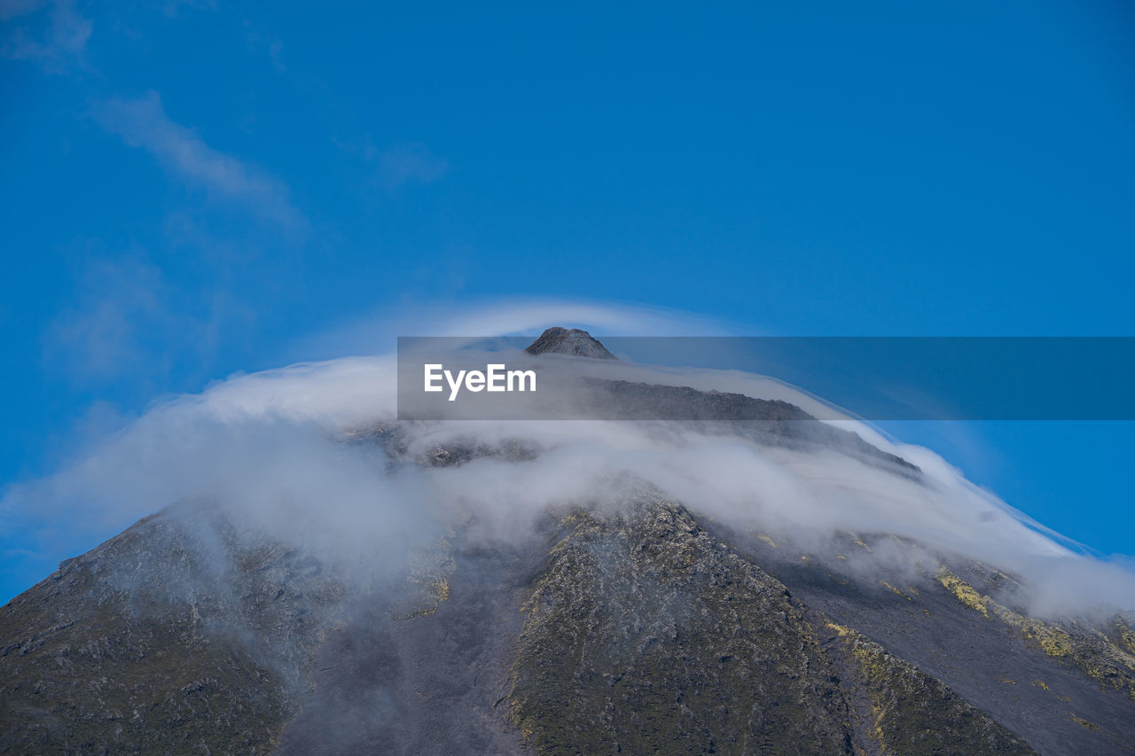 AERIAL VIEW OF VOLCANIC MOUNTAIN AGAINST BLUE SKY