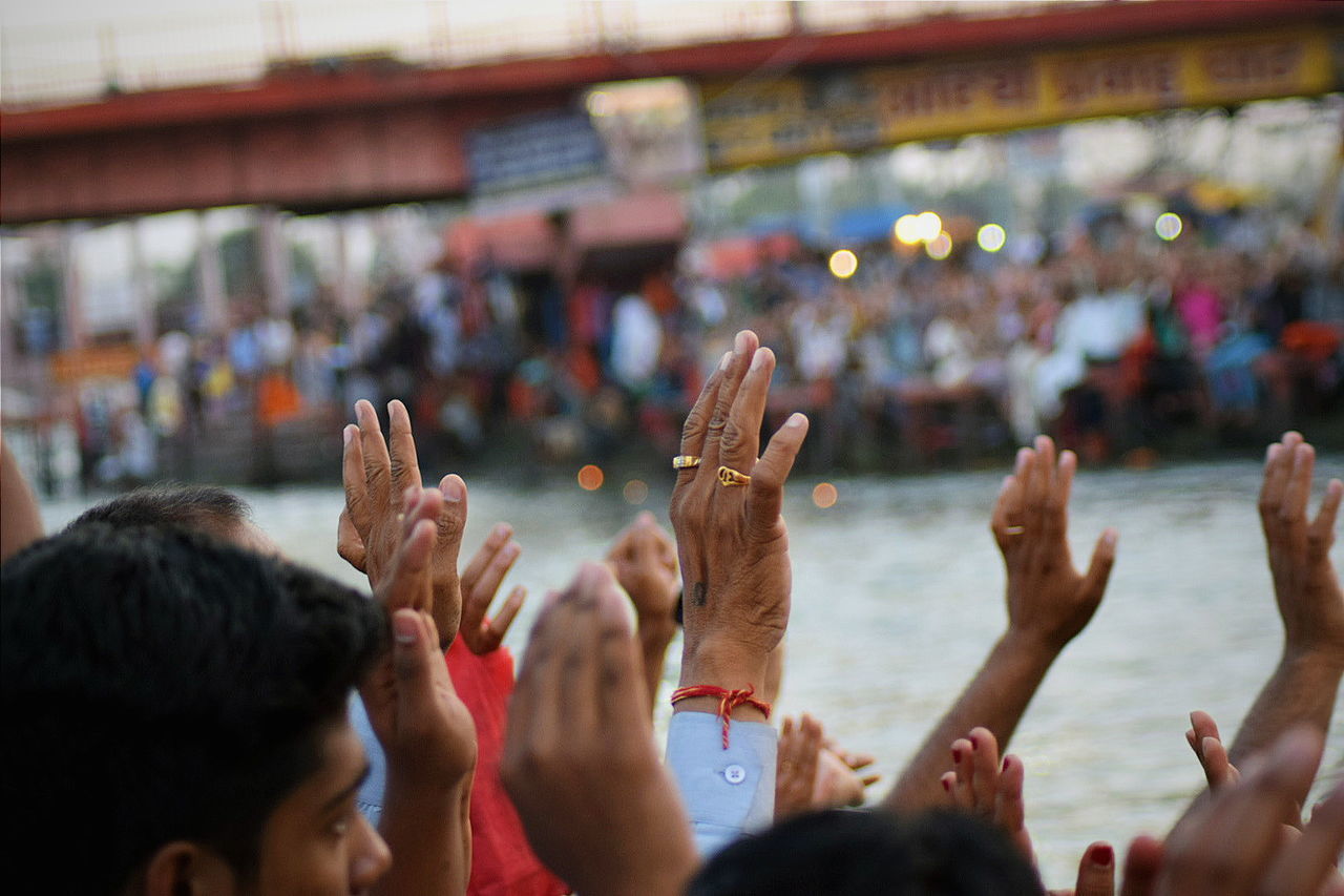 People with arms raised during religious festival by river