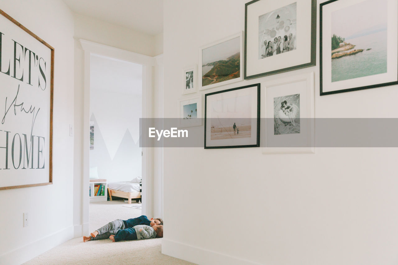 Siblings lying in corridor at home