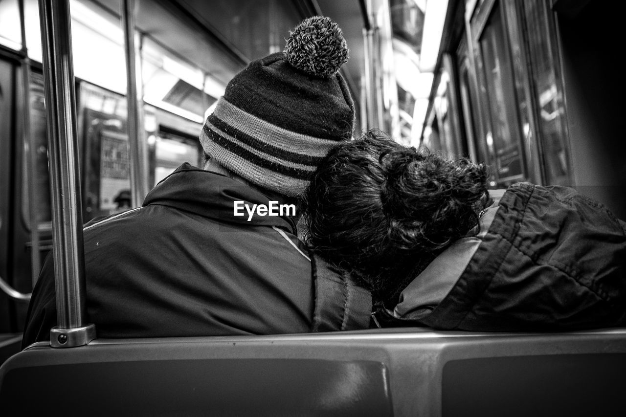 Rear view of couple traveling on subway train