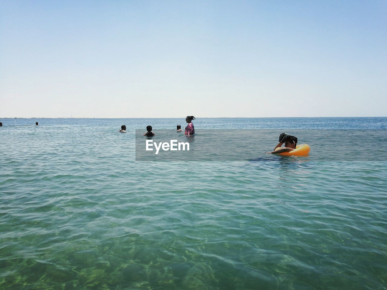 People swimming in sea against clear sky