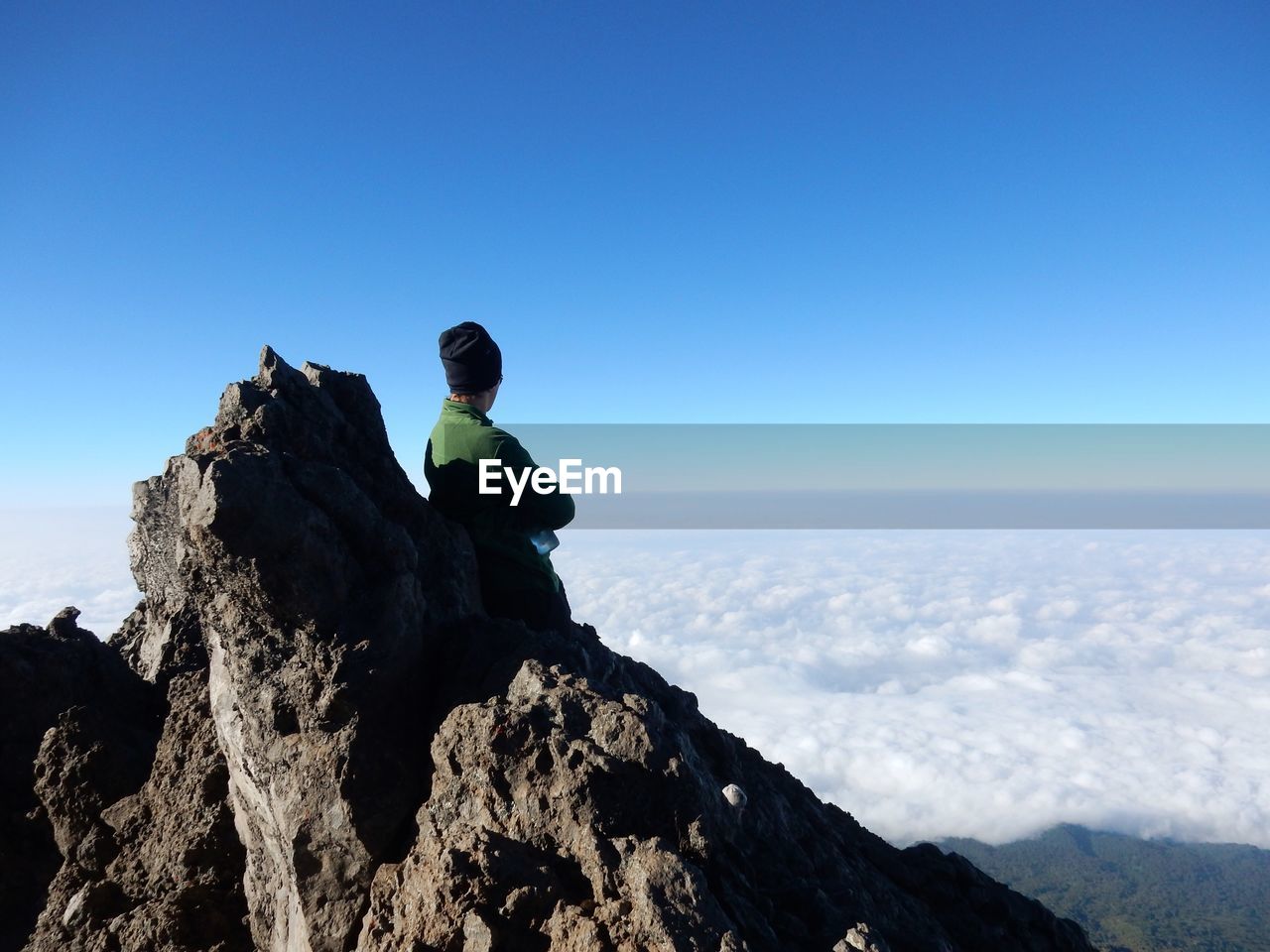 Hiker standing on peak looking at cloudscape