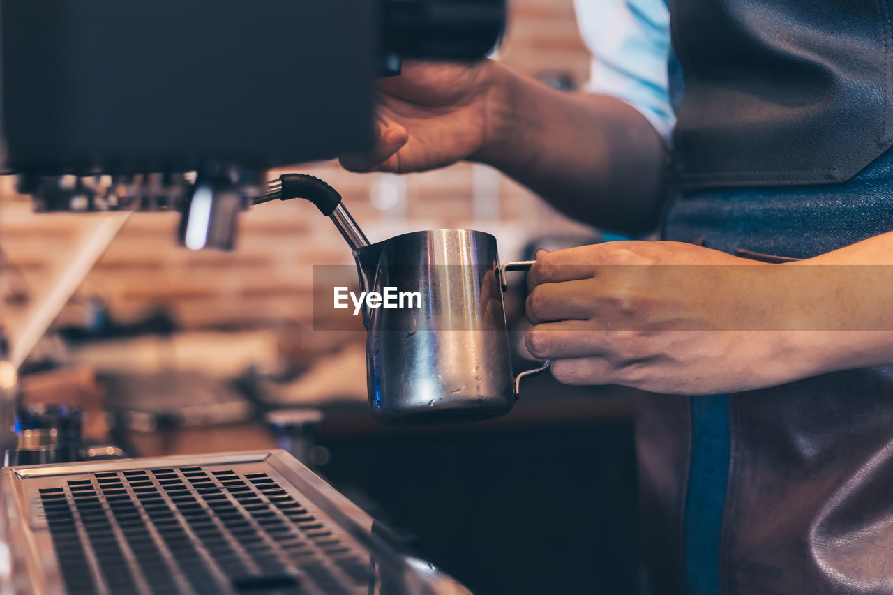 Midsection of man preparing coffee in cafe