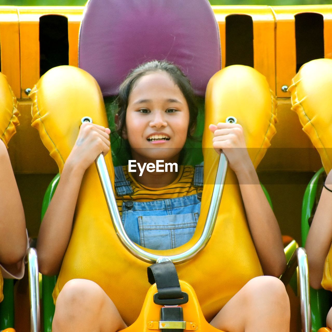 PORTRAIT OF HAPPY GIRL SITTING ON YELLOW AND SMILING