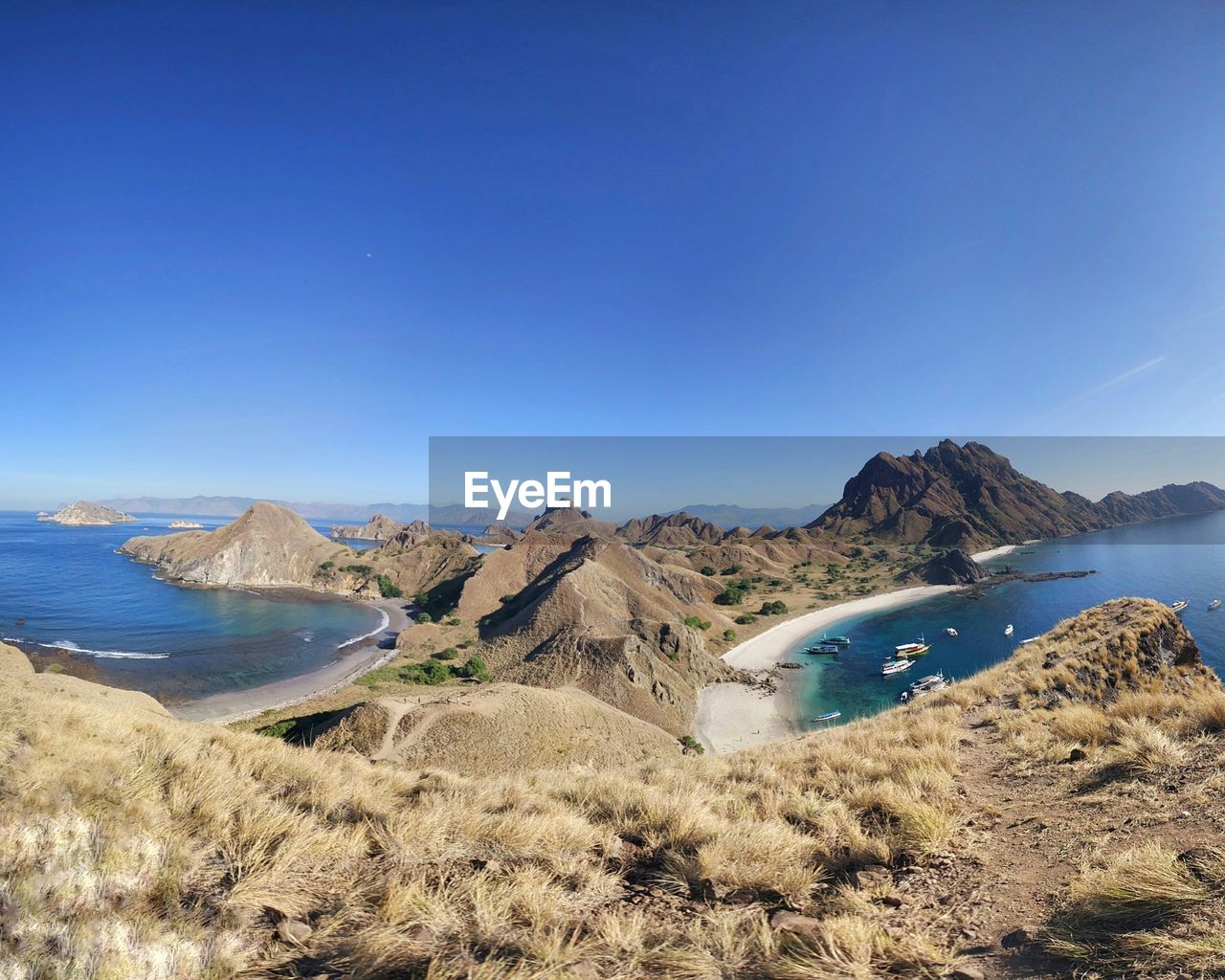 Panoramic view of sea and mountains against clear blue sky