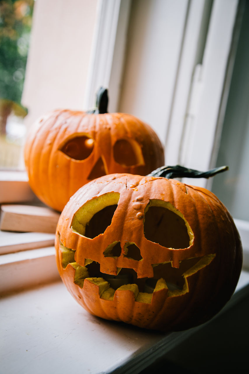 Close up of jack o lanterns, carved pumpkins on window sill for halloween