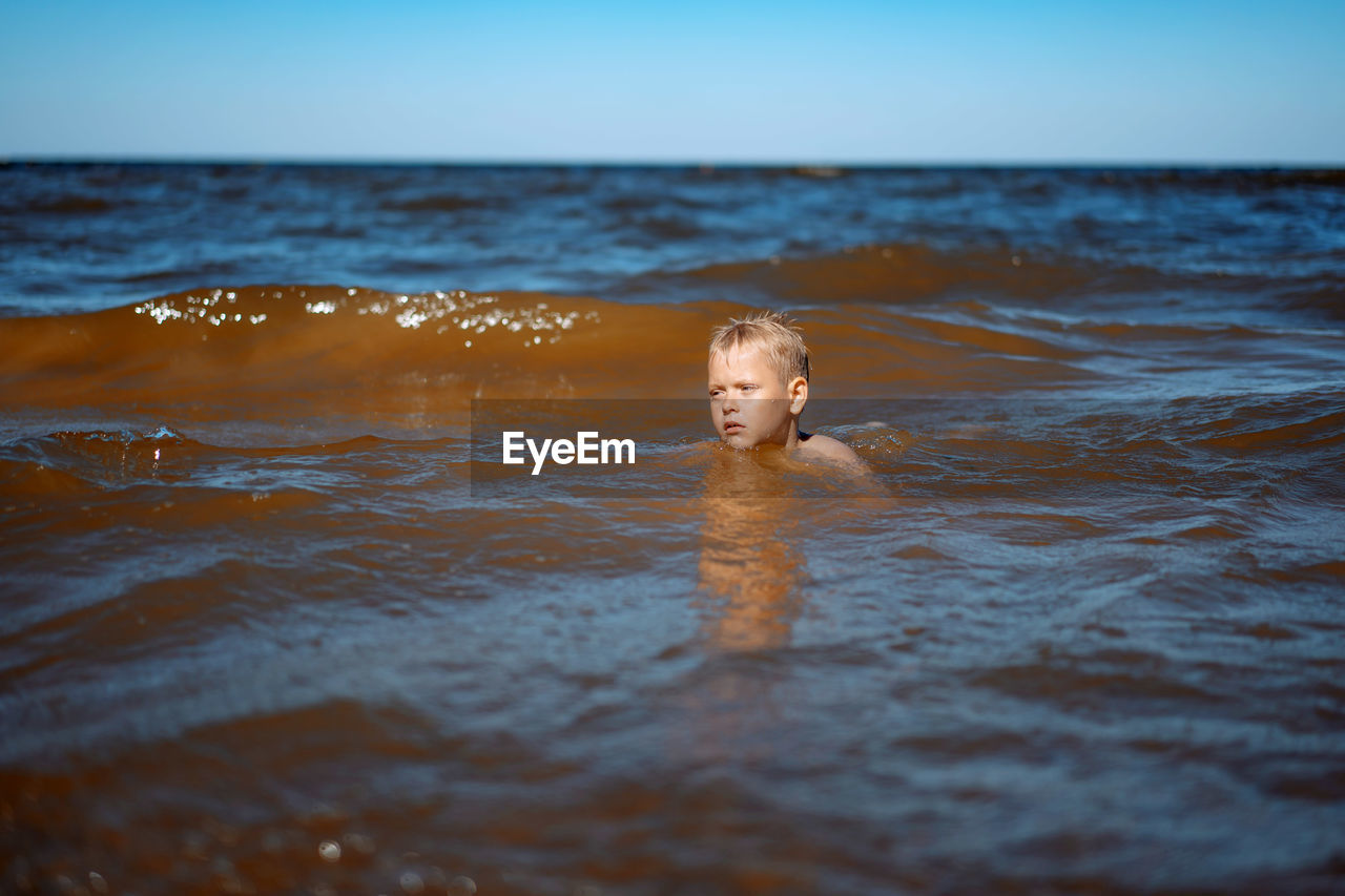 7-8 years old cute caucasian boy swimming in the sea