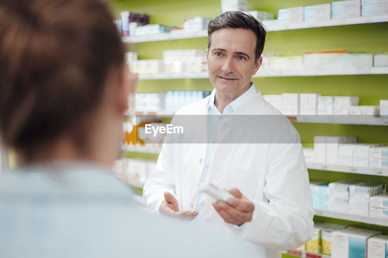 adult, occupation, pharmacy, healthcare and medicine, men, business, lab coat, indoors, medicine, pharmacist, two people, medical, working, retail, women, store, smiling, chemist, clothing, person, customer, mature adult, standing, talking, scientist, expertise, communication, service, laboratory, pharmaceutical drug, shelf, professional occupation, portrait, drug, female, sales clerk