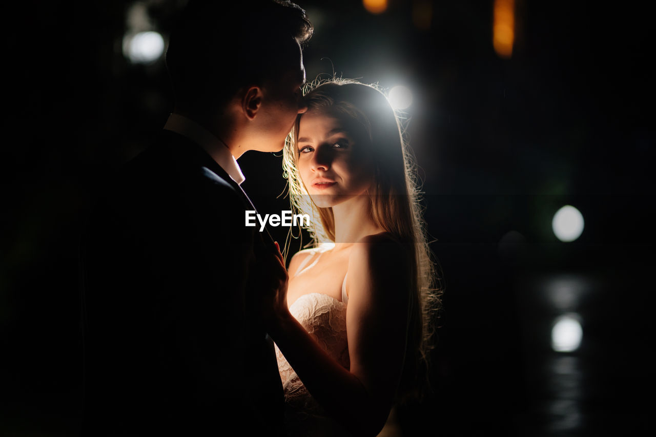 Young couple standing at illuminated night