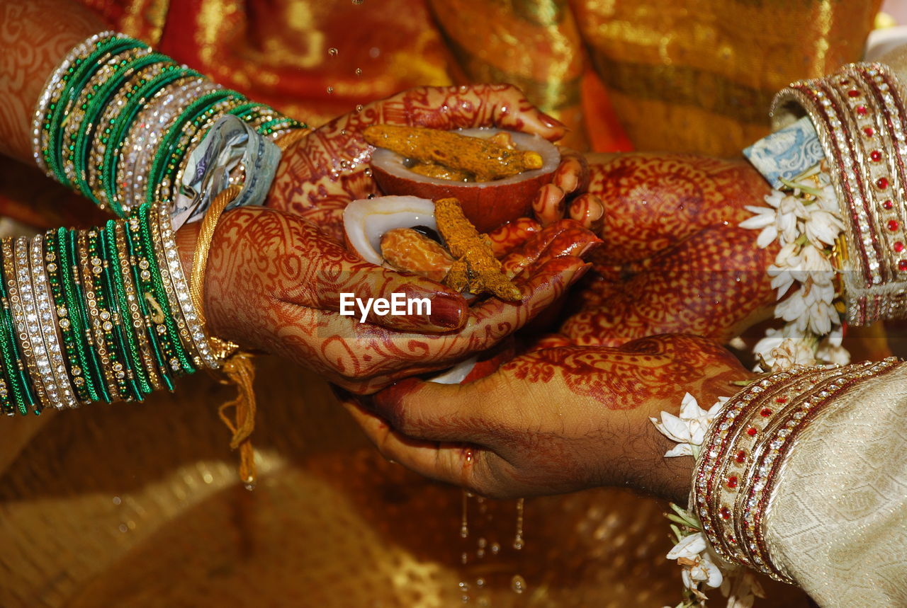 Cropped hand of couple holding food in hand during wedding rituals